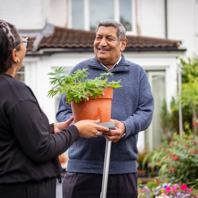 A man and woman stand side by side, each holding a vibrant plant pot.