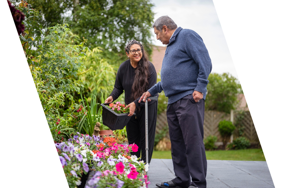 Two people, a woman and a man, are tending to flowers in a garden.