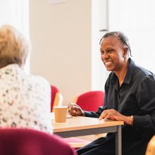 A younger woman and an older woman sit together at a table, engaged in a thoughtful discussion 