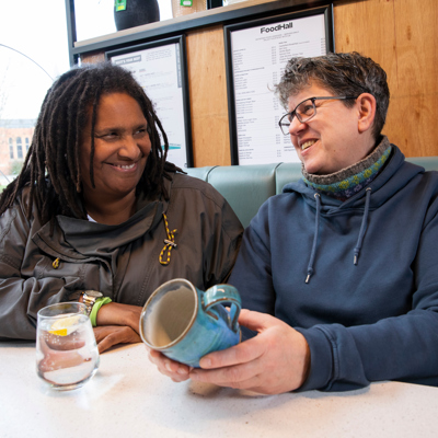 Two women seated at a table, enjoying a conversation over cups of coffee.